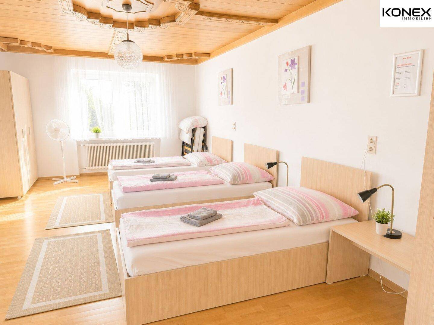 Geräumiges Schlafzimmer mit drei Einzelbetten, Holzboden und einer dekorativen Holzdecke.