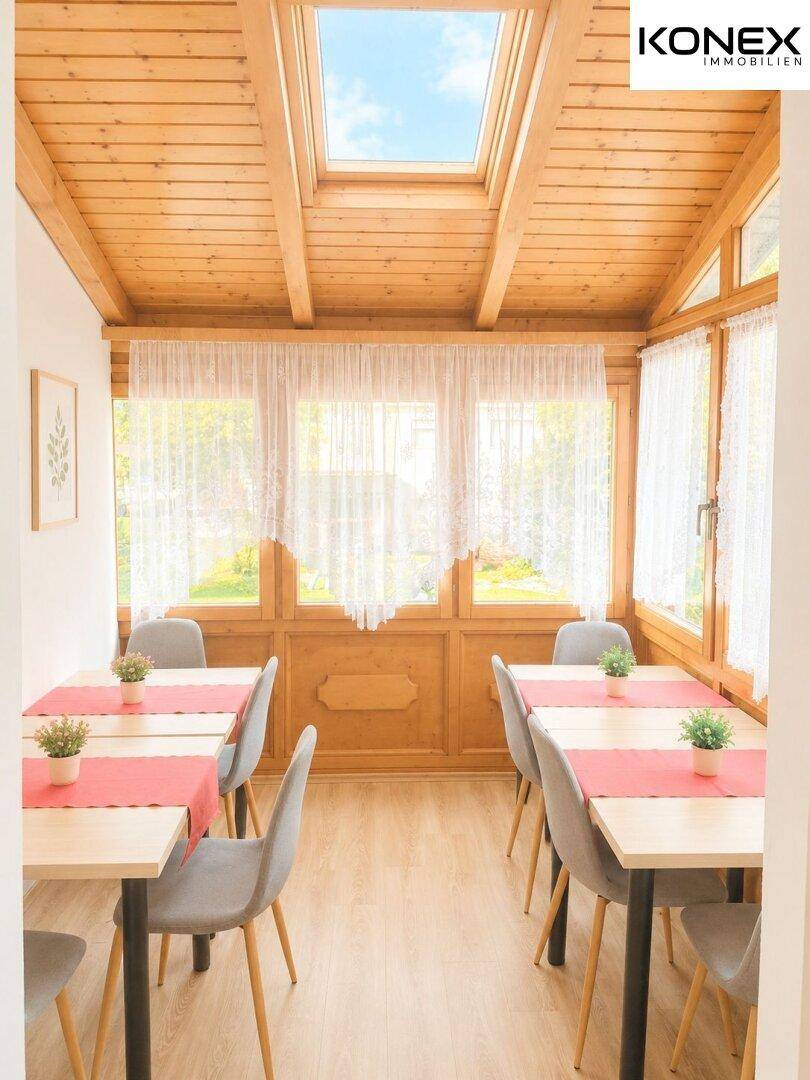 Heller Essbereich mit Holztischen, Holzdecke und einem Dachfenster für viel Tageslicht.