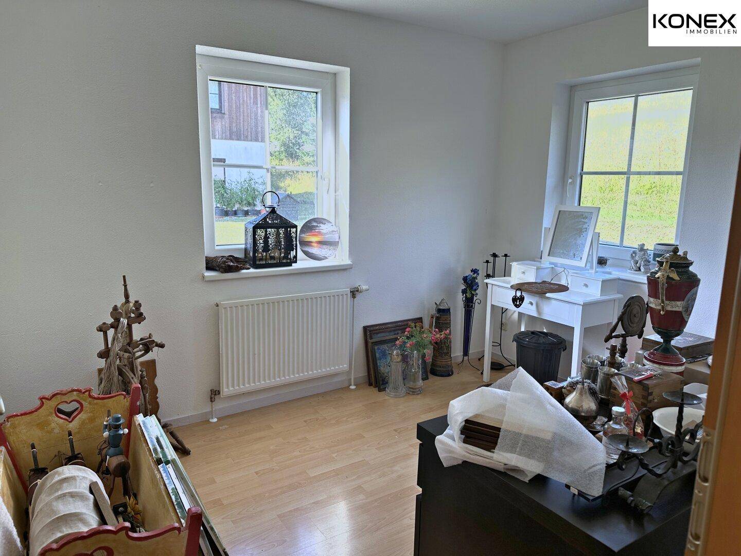 Schlafzimmer oder Ankleidezimmer mit hellem Laminatboden und zwei Fenstern.