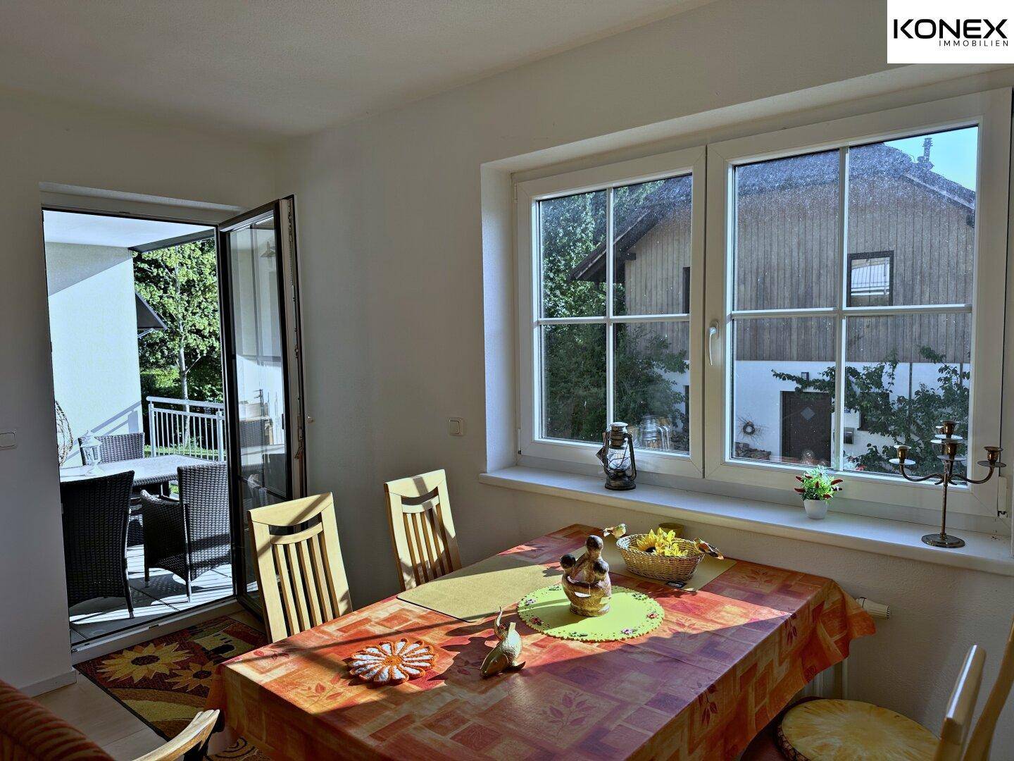 Heller Essbereich mit Holztisch und Zugang zu einem möblierten Balkon.