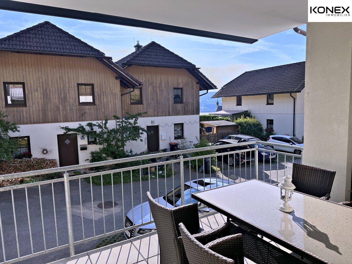 Sonniger Balkon mit Outdoor-Möbeln und Blick auf die Nachbarschaft.