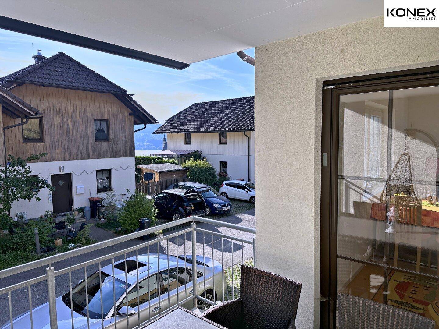 Balkon mit Sitzgelegenheiten und Ausblick auf die umliegenden Gebäude und Parkplätze.