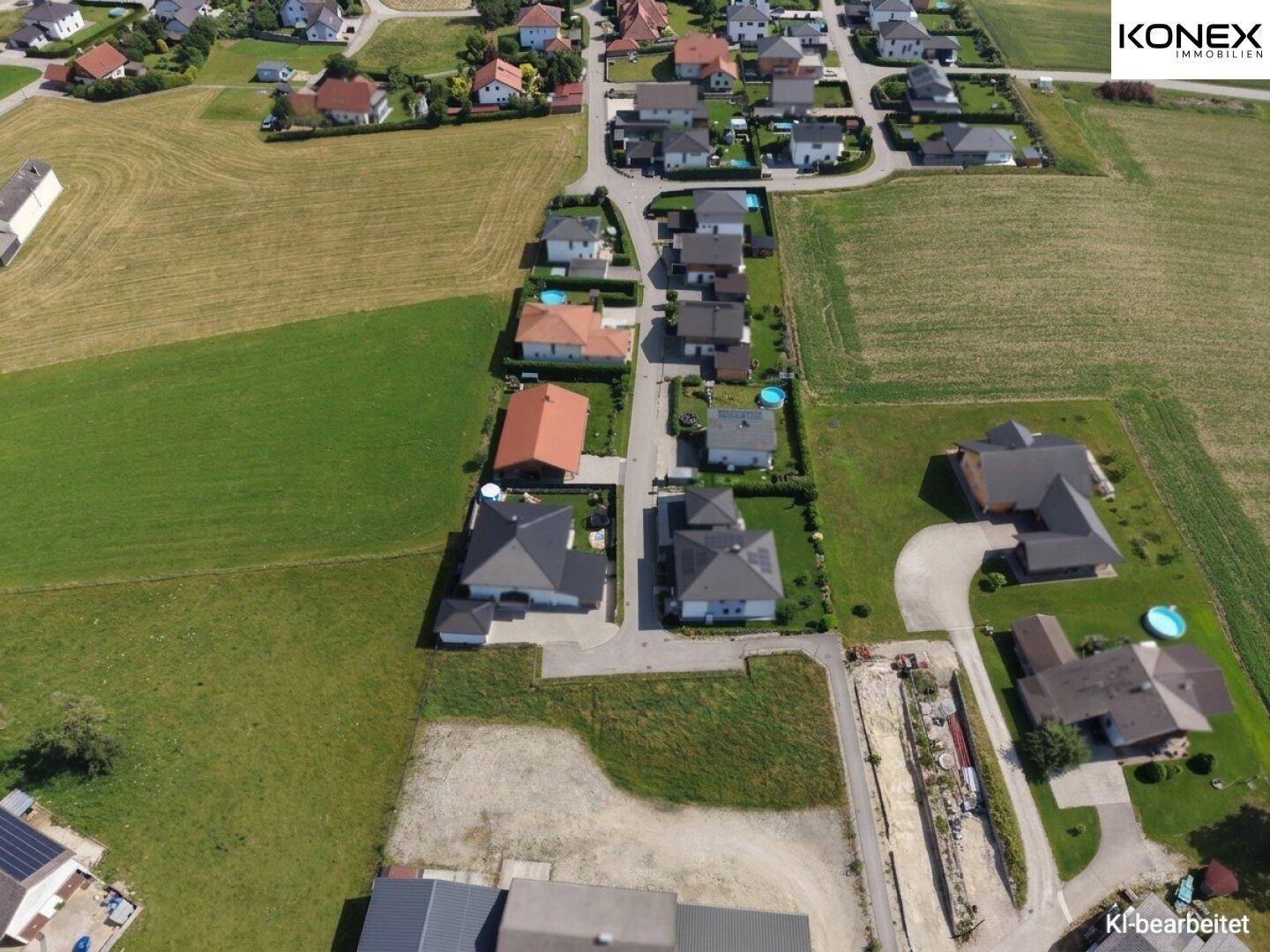 Weitläufige Luftaufnahme eines Wohngebiets mit vielen Einfamilienhäusern und angrenzenden Feldern.