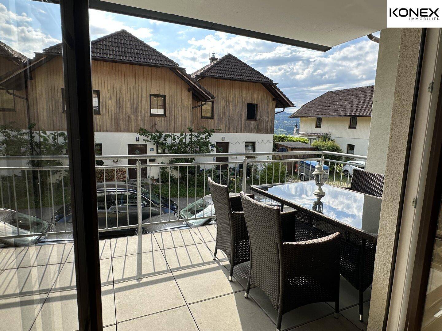Möblierter Balkon mit Esstisch und Stühlen, bietet Blick auf die umliegenden Häuser.