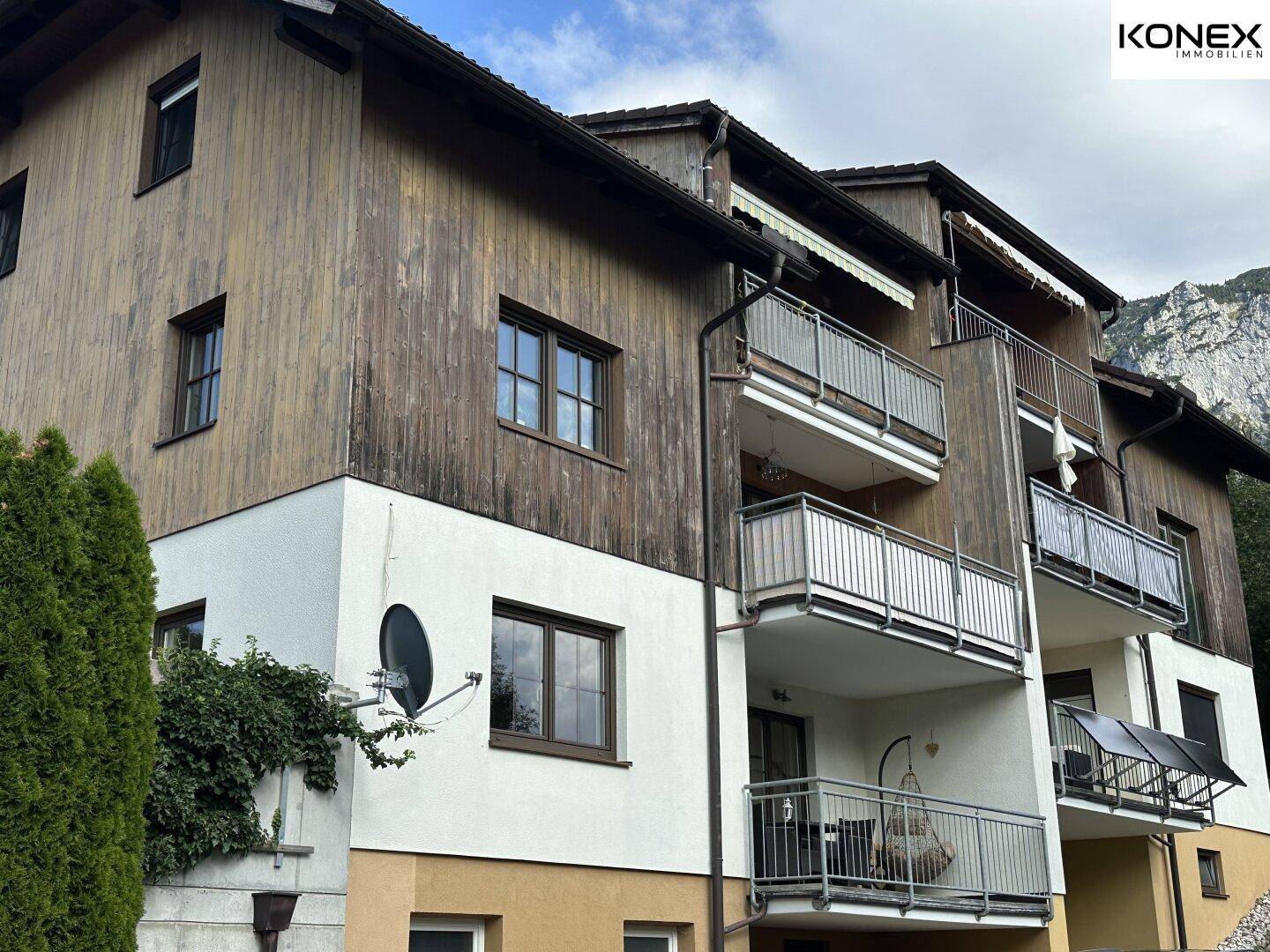 Fassade eines Mehrfamilienhauses mit mehreren Balkonen und Holzverkleidung.