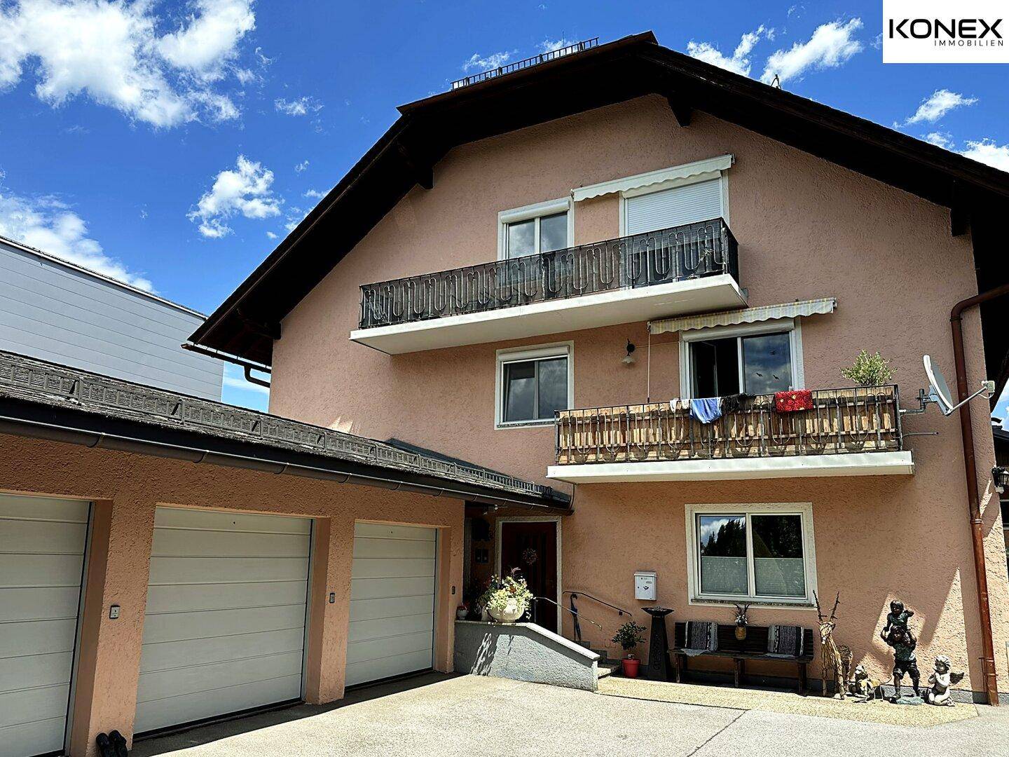 Vorderansicht des Wohnhauses mit zwei Balkonen und integrierter Doppelgarage.