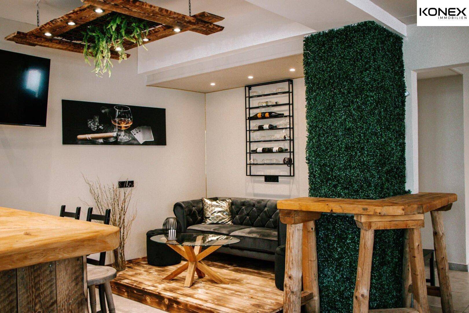 Entspannter Loungebereich mit bequemer Couch, Couchtisch und dekorativer Weinregalwand.