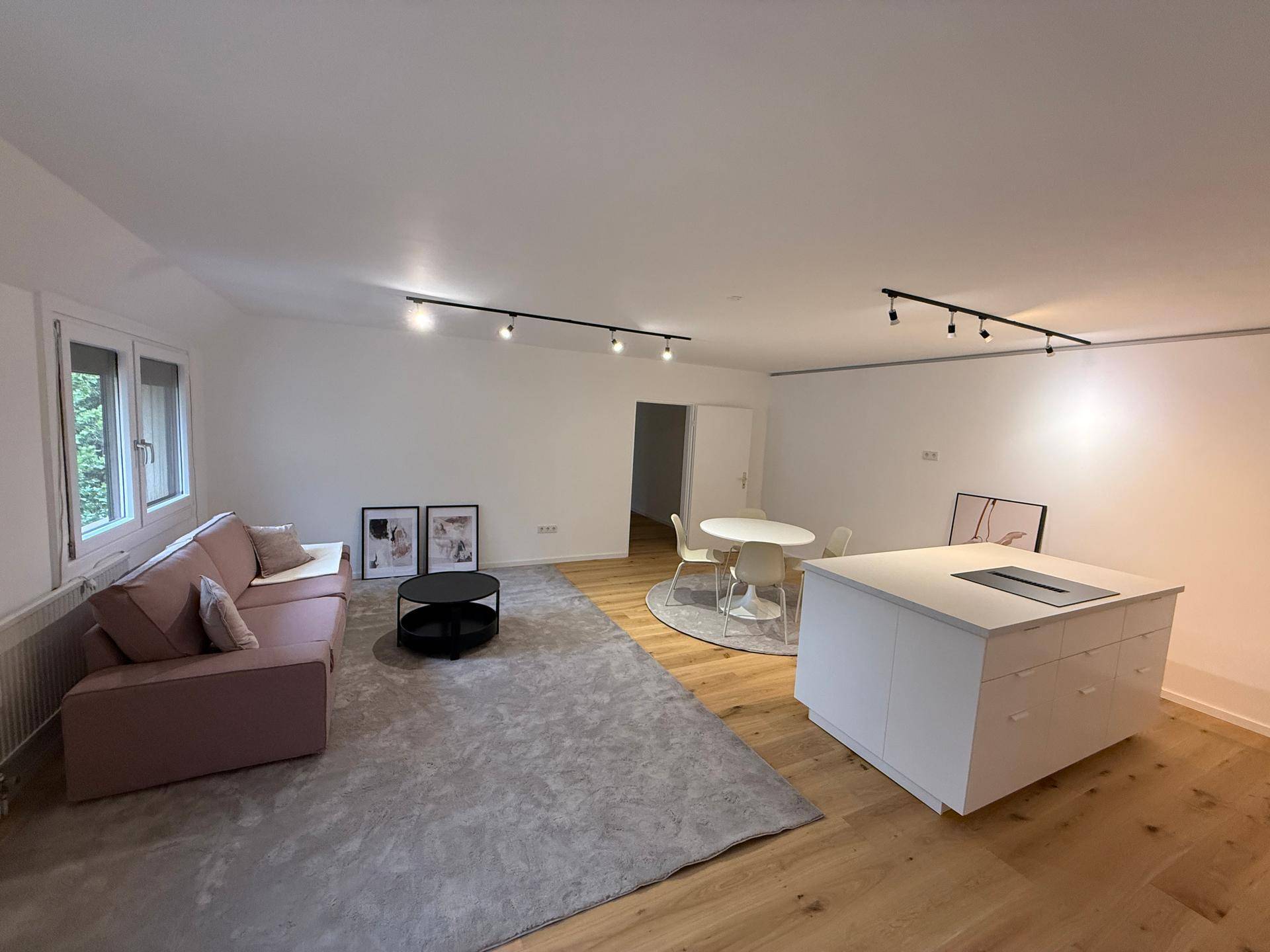 Geräumiger offener Wohnbereich mit Kücheninsel, Esstisch und gemütlichem Sofa.