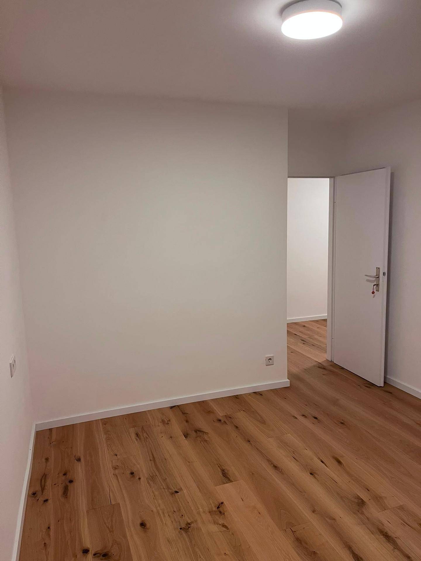Helles Zimmer mit Holzboden und weiß gestrichenen Wänden, bereit zur Einrichtung.