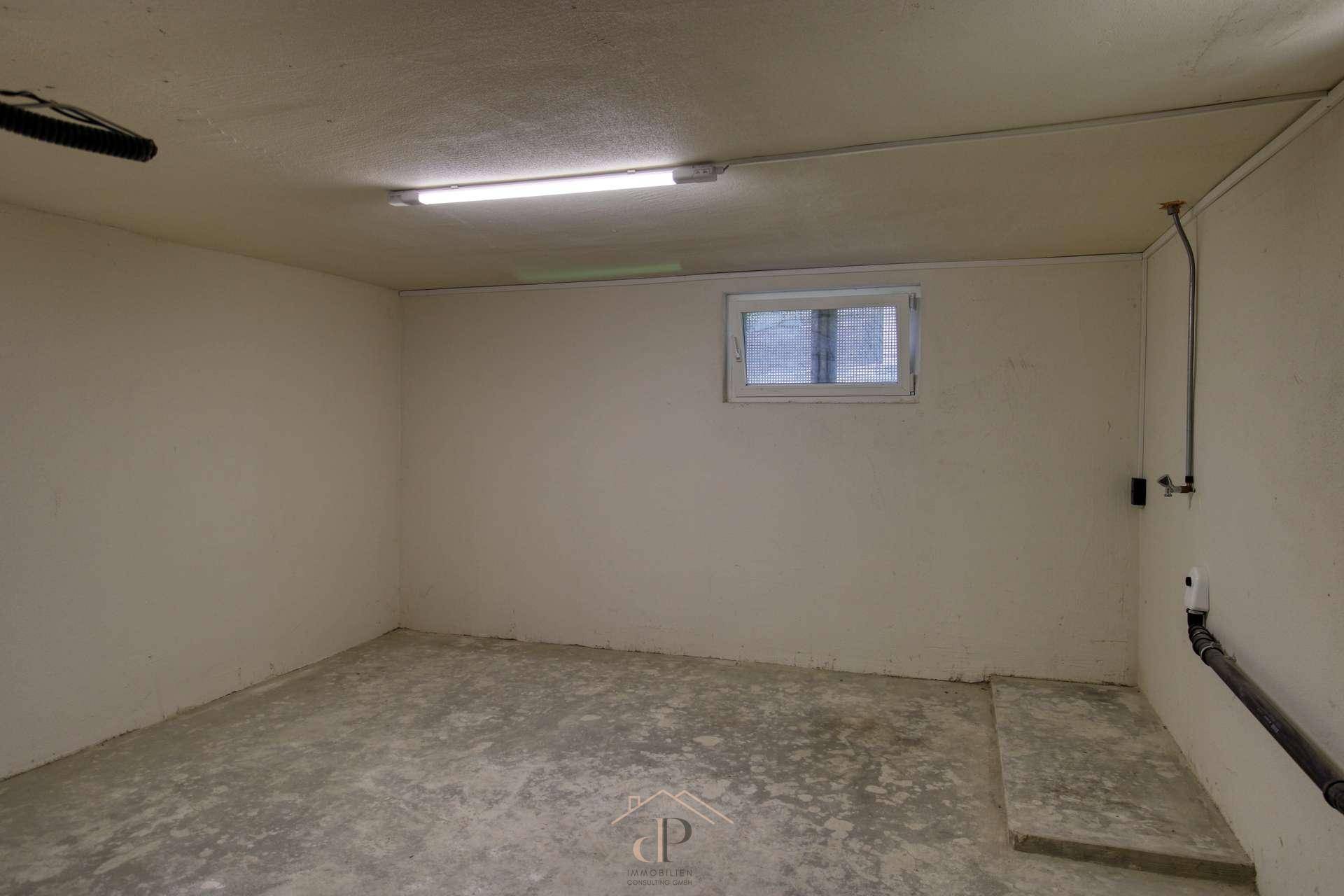 Geräumiger Kellerraum mit Betonboden und kleinem Fenster, ideal als Lager- oder Hobbyraum.