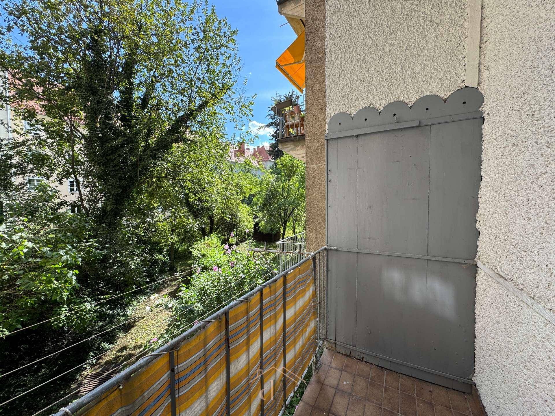 Balkon mit Blick auf den grünen Innenhof und die umliegenden Gebäude.