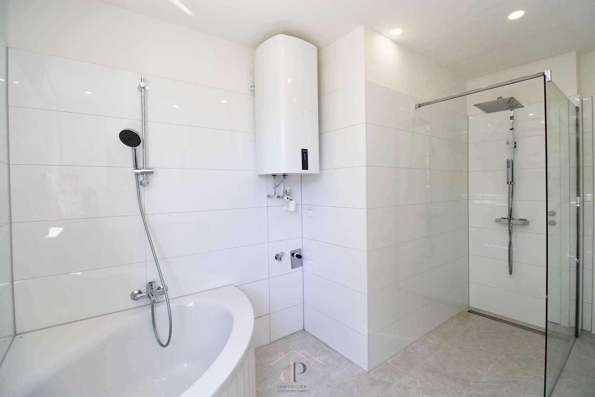 Modernes Badezimmer mit Badewanne, ebenerdiger Dusche und weißem Boiler.