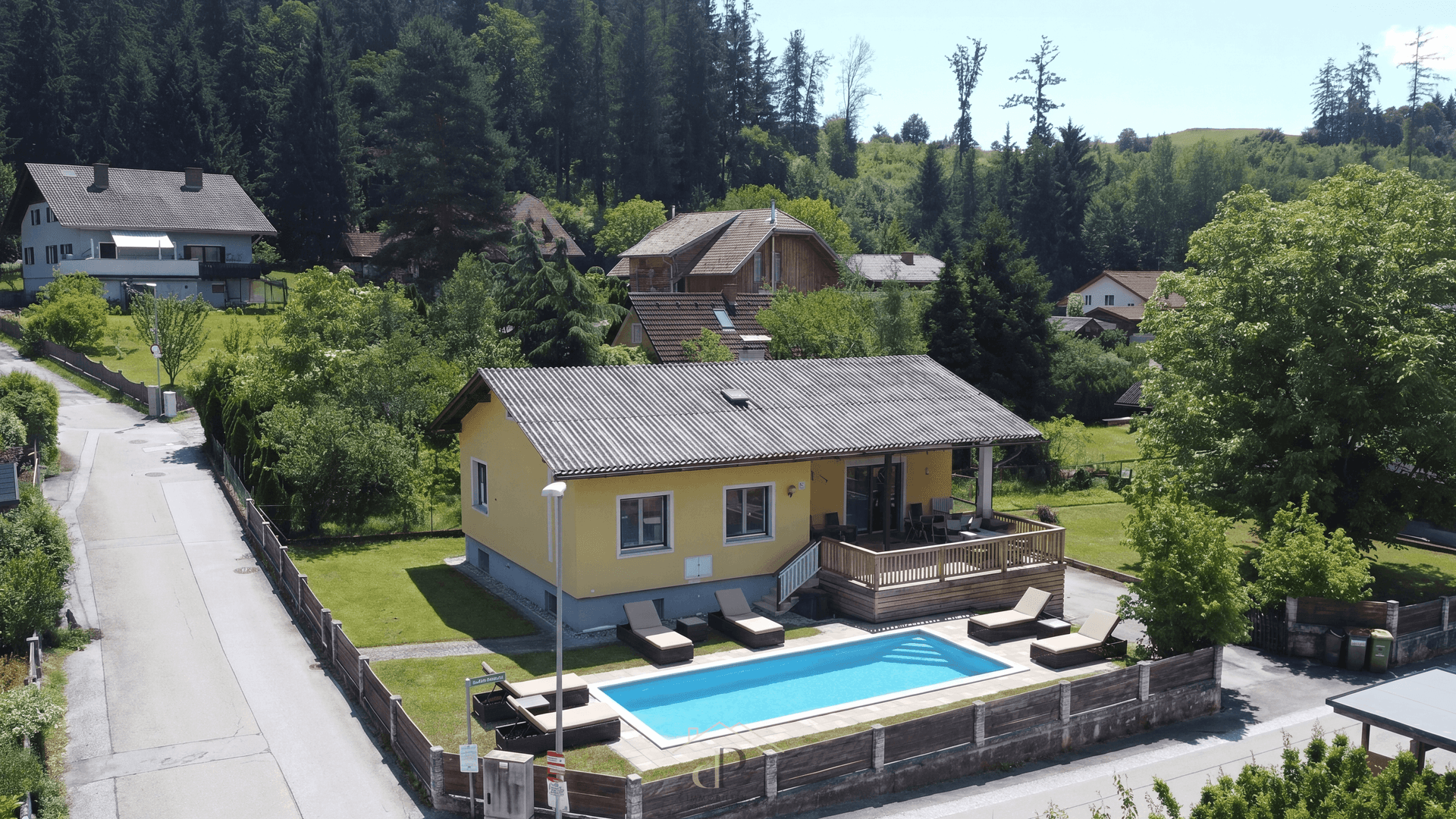 Luftaufnahme des Hauses mit großem Pool, Sonnenterrasse und Liegestühlen im Gartenbereich.