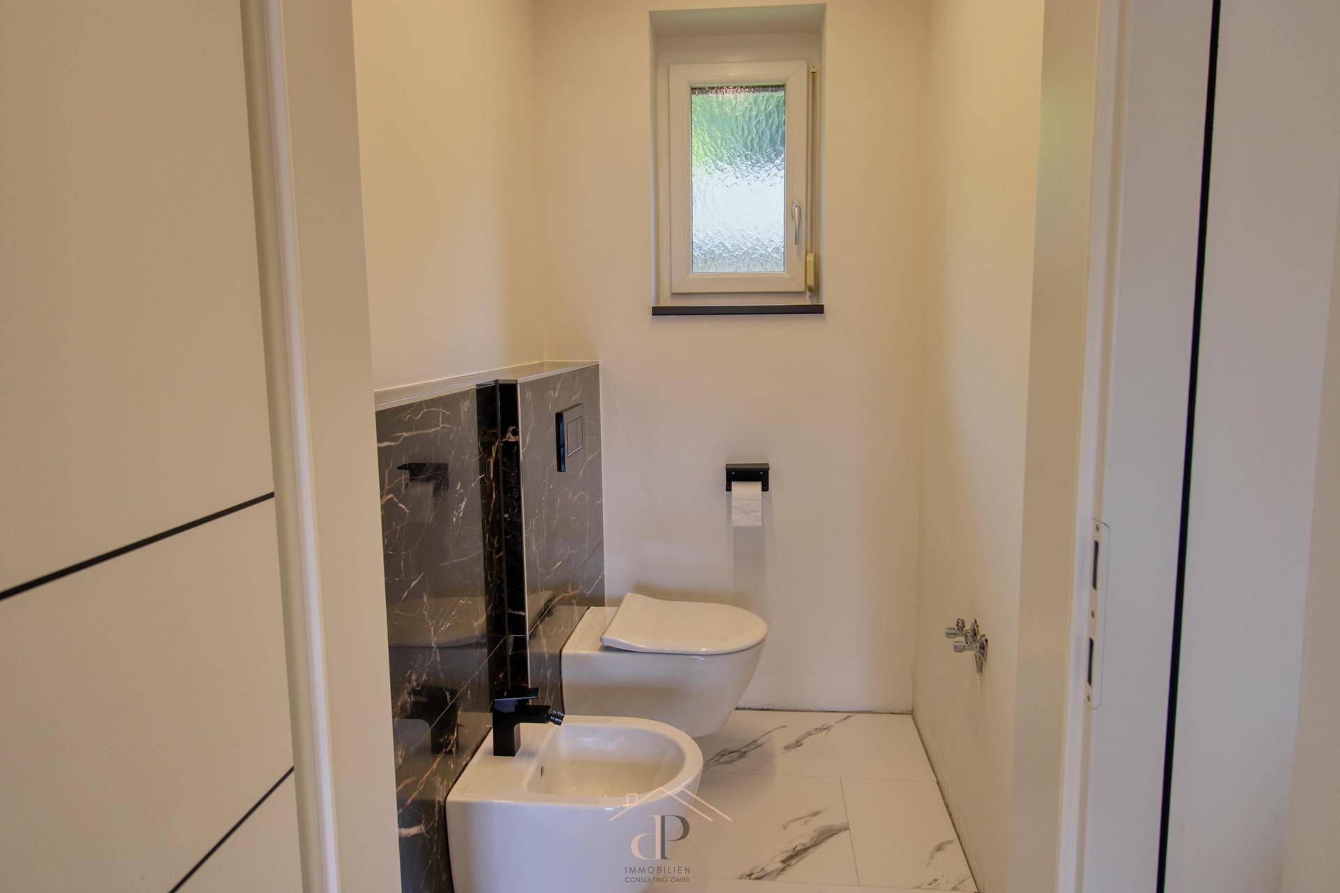 Modernes Gäste-WC mit wandhängender Toilette, Bidet und Fenster, elegant gestaltet.