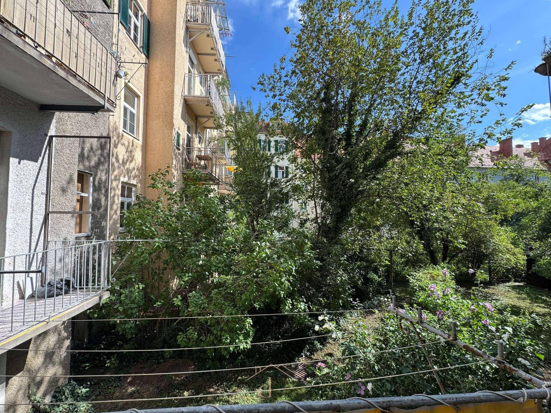 Balkon mit weitem Blick auf den grünen Innenhof und die umliegenden Gebäude.