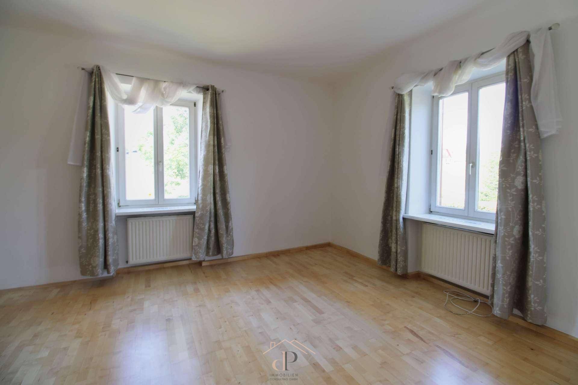 Helles Schlafzimmer mit Holzboden und zwei Fenstern, bietet viel Tageslicht und eine ruhige Atmosphäre.