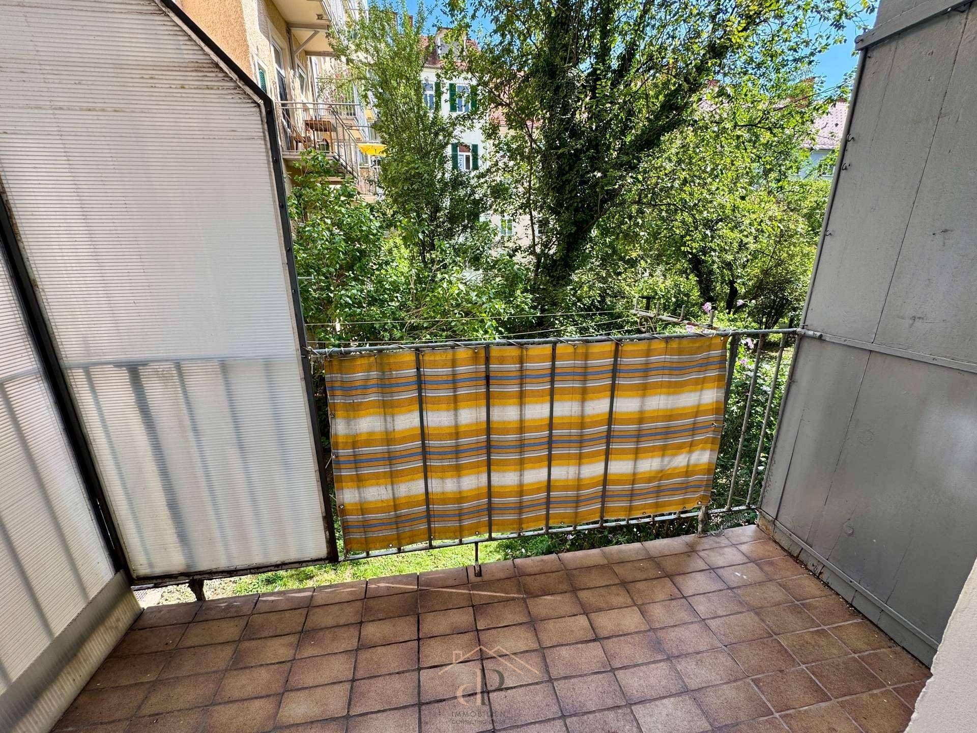 Kleiner Balkon mit Fliesenboden und Blick ins Grüne, ideal für entspannte Stunden.