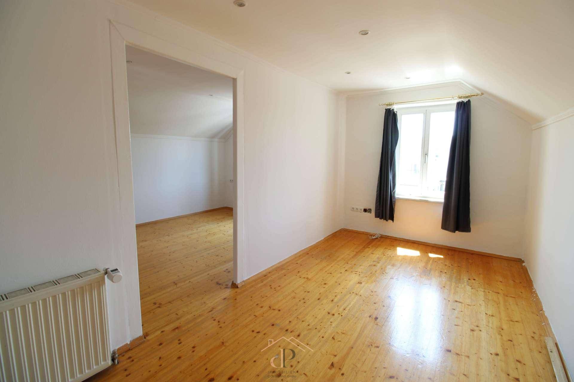 Helles Schlafzimmer im Dachgeschoss mit Holzboden und Dachschräge, bietet eine gemütliche Wohnatmosphäre.