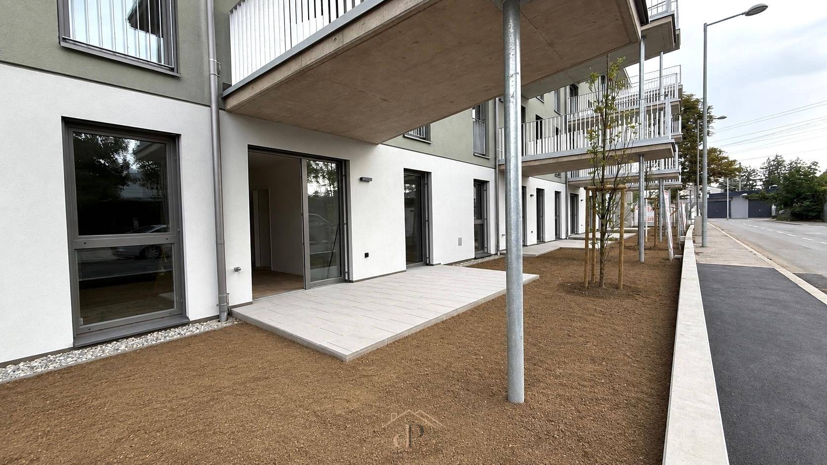 Außenansicht eines Neubaus mit Terrassen im Erdgeschoss und darüberliegenden Balkonen.