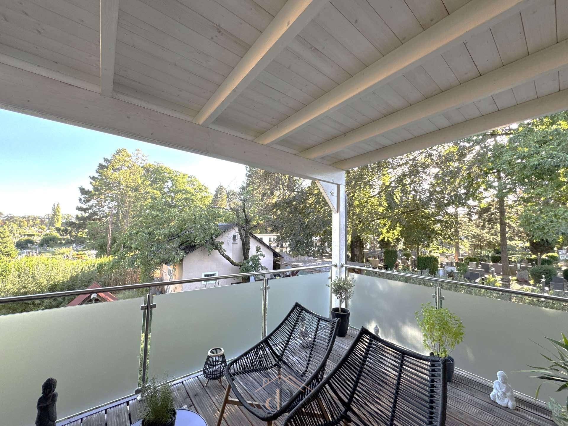 Helle überdachte Terrasse mit Holzdeck, bequemen Möbeln und Panoramablick ins Grüne.