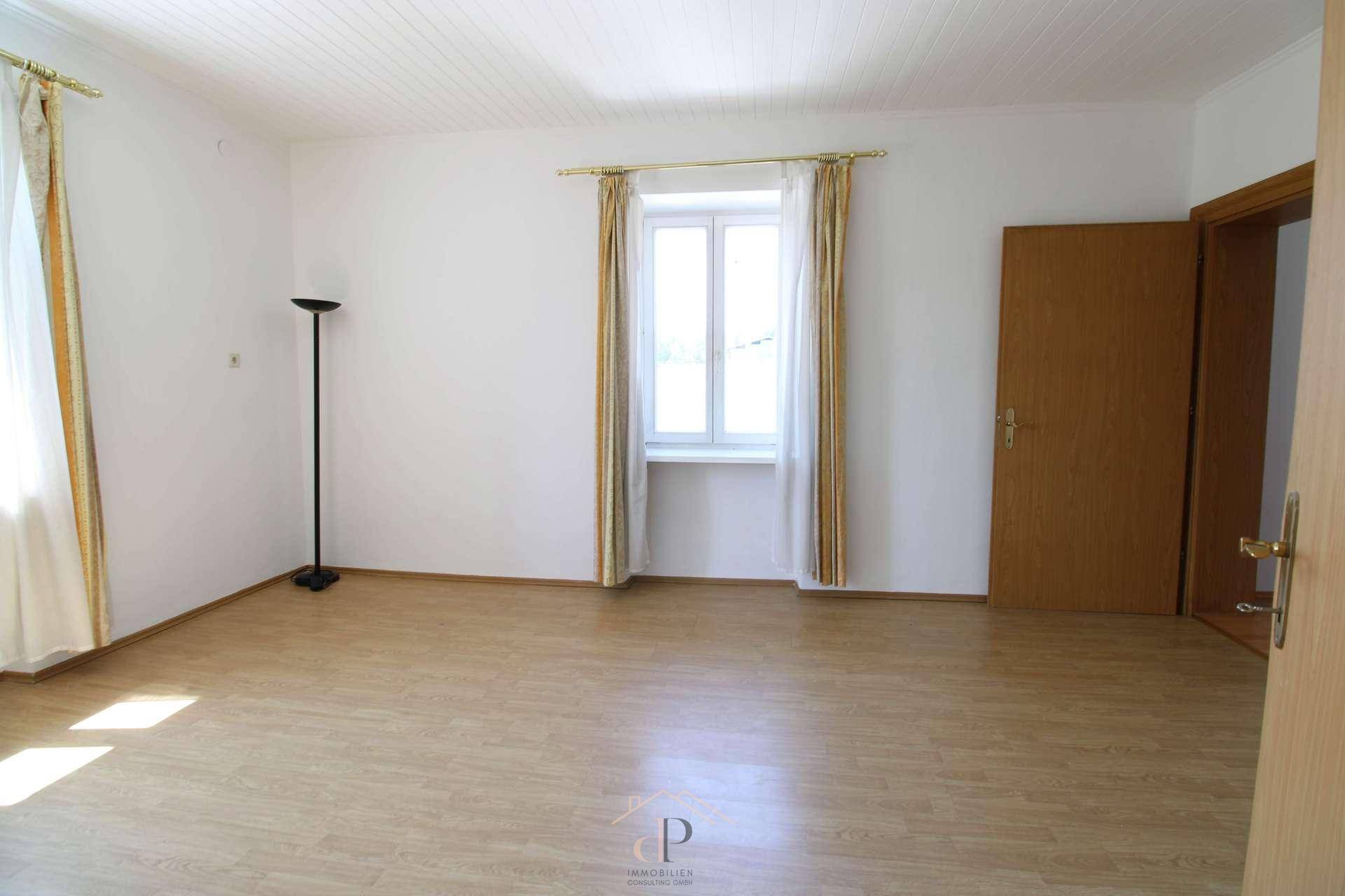 Freundliches Zimmer mit hellem Laminatboden und großem Fenster, bietet eine angenehme Wohnatmosphäre.