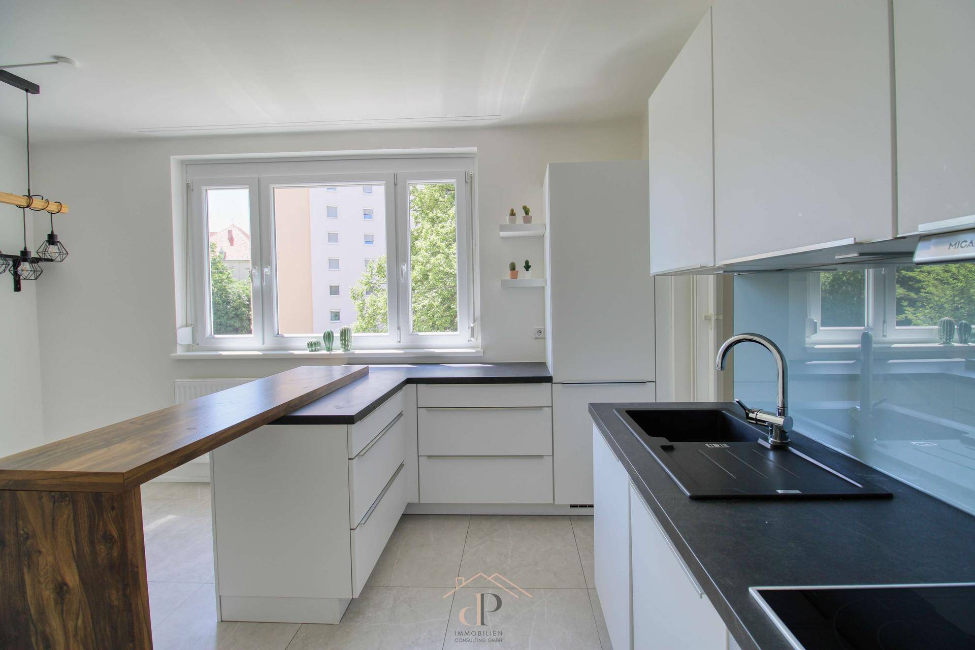Moderne Einbauküche mit weißen Fronten, dunkler Arbeitsplatte und integriertem Spülbecken.