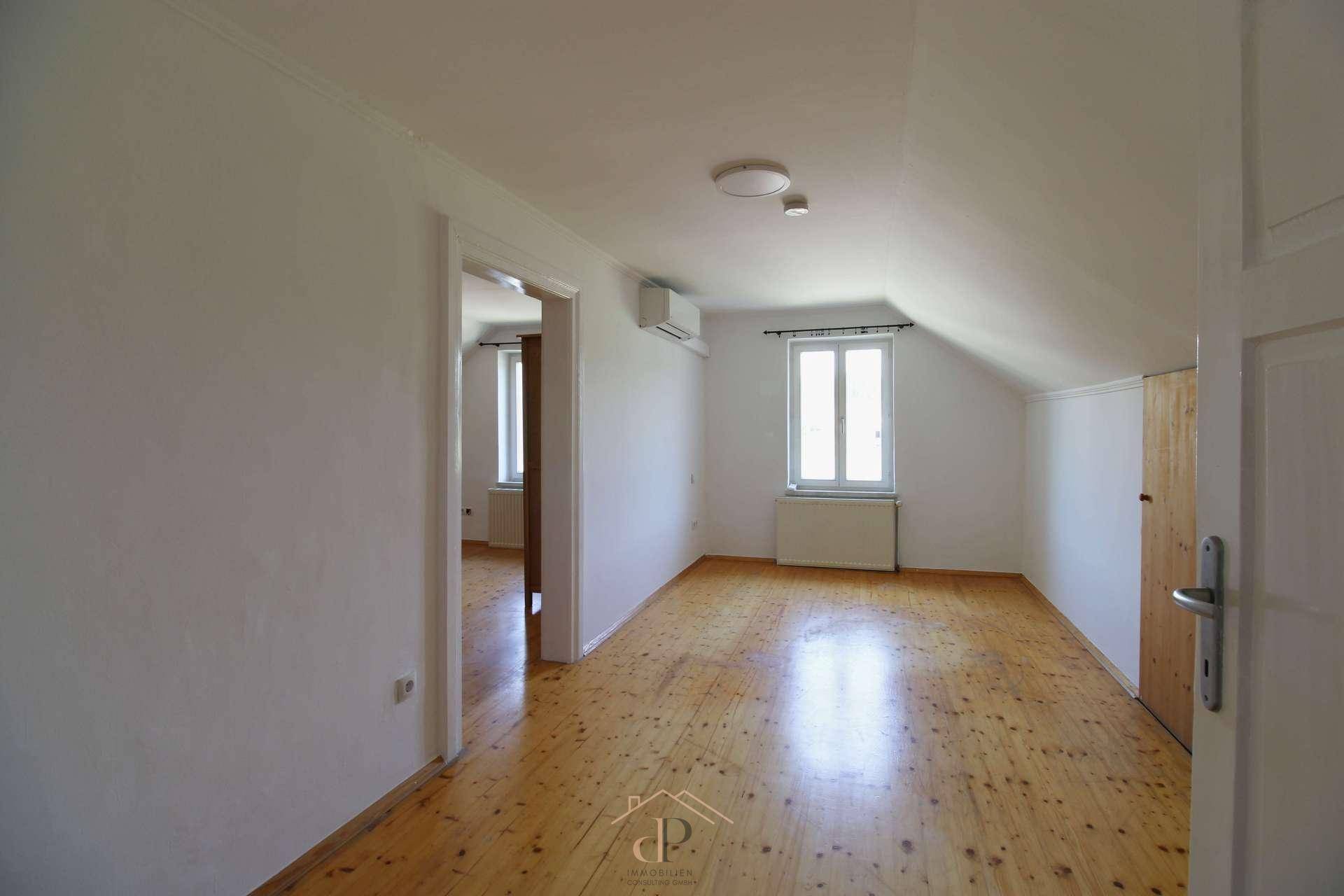 Geräumiges Schlafzimmer im Dachgeschoss mit Holzboden, Klimaanlage und Dachschräge, hell und komfortabel.