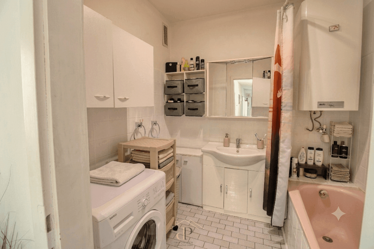 Badezimmer mit rosa Badewanne, Waschbecken und Waschmaschine, gefliest in Weiß.