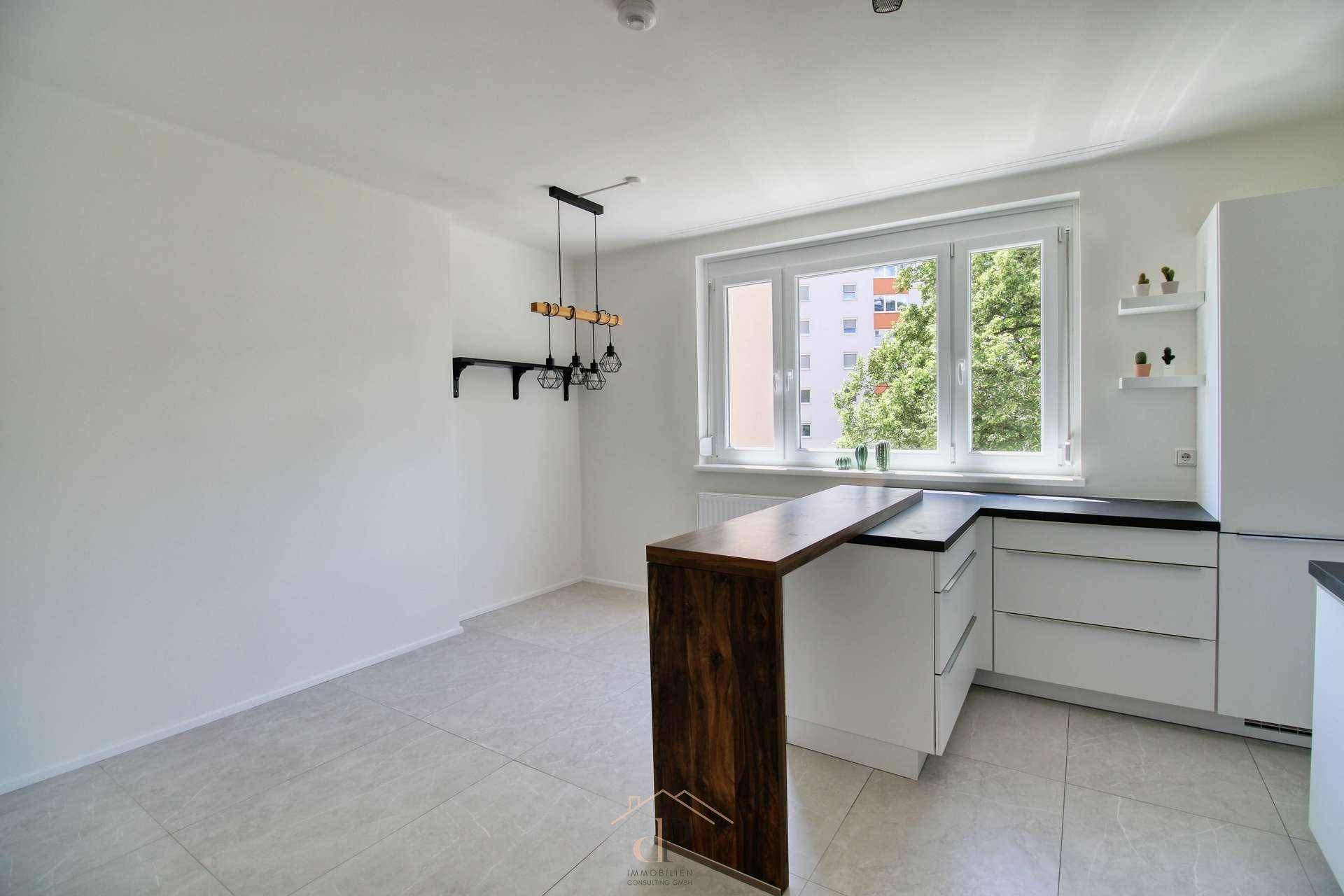 Offener Wohnküchenbereich mit Küchenzeile, Insel und Blick auf die Stadt.