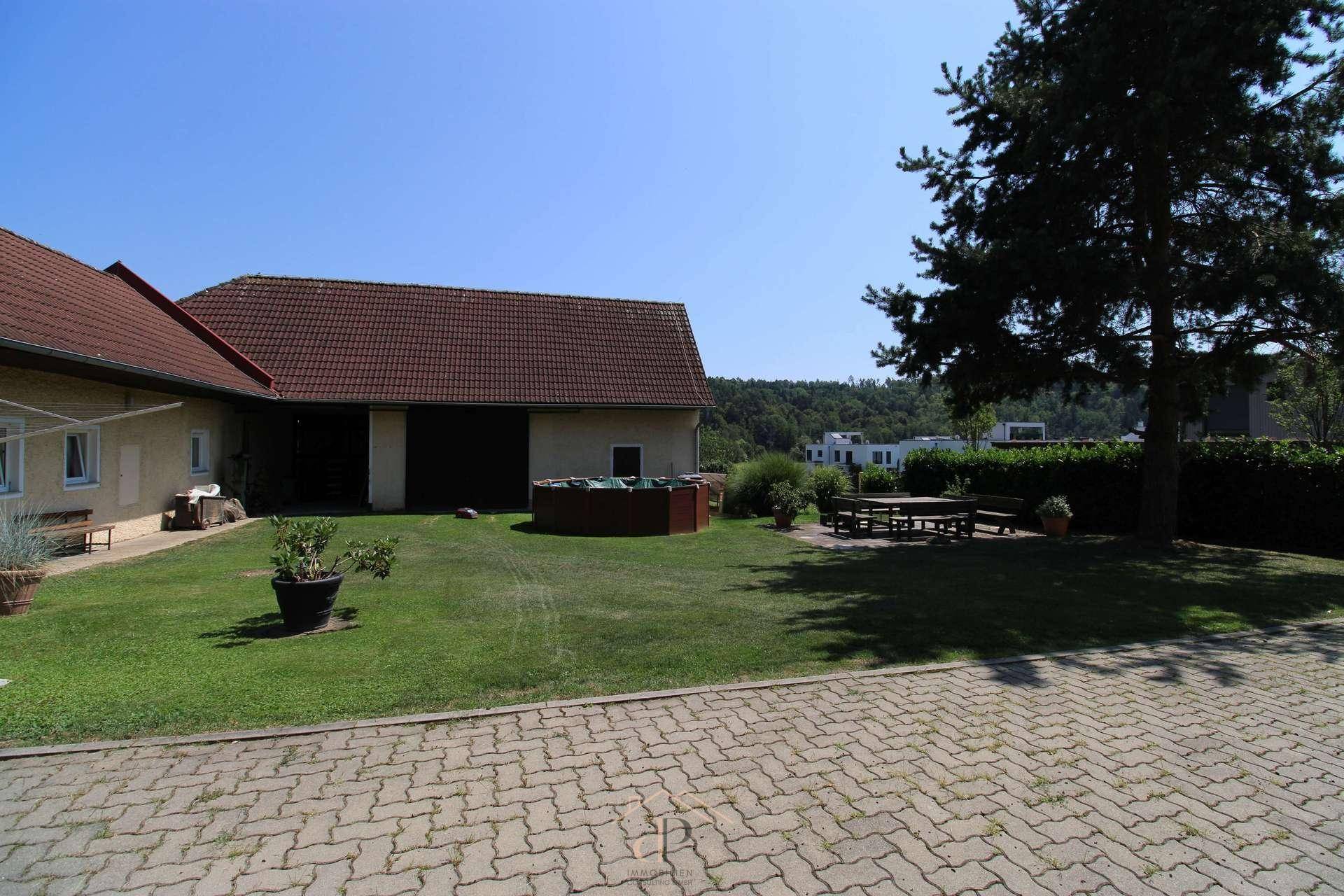 Weitläufiger Garten mit gepflastertem Bereich, Rasenfläche und Sitzgelegenheiten, ideal für Entspannung im Freien.
