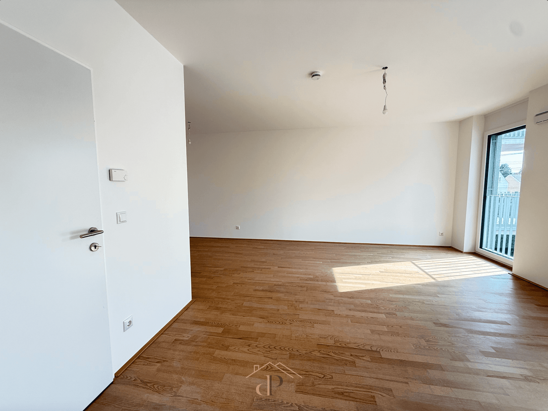 Geräumiger, unmöblierter Raum mit Parkettboden und viel Tageslicht.
