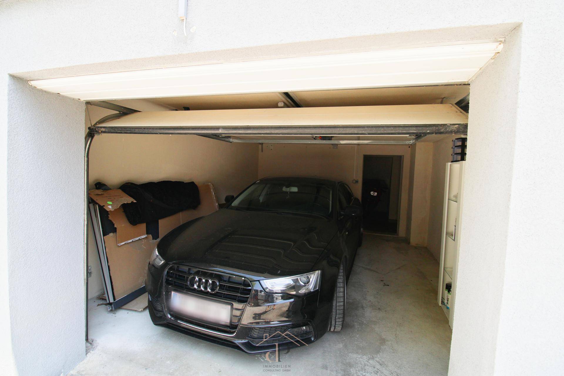 Garage mit einem geparkten Auto und Stauraum, sicher und praktisch.