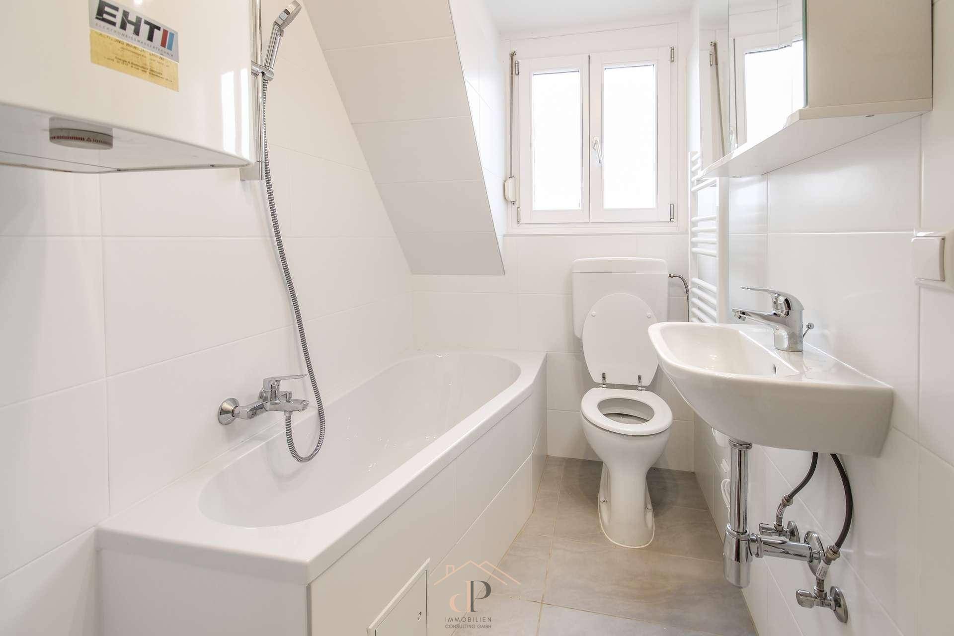 Modernes Badezimmer mit Badewanne, WC, Waschbecken und Fenster im Dachgeschoss.