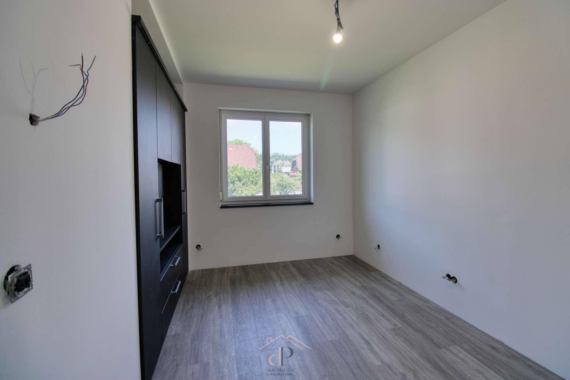 Leerer Raum mit integriertem schwarzen Kleiderschrank und Fenster, vielseitig nutzbar.