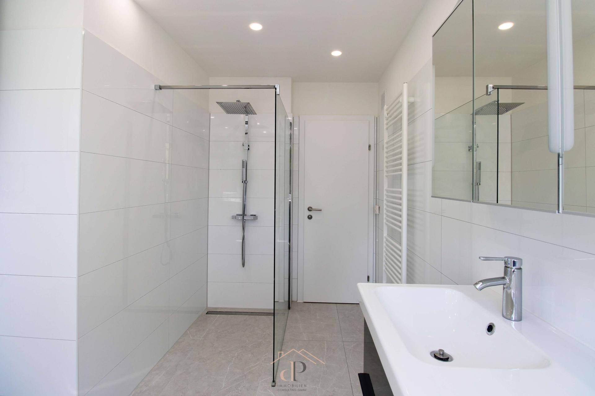 Modernes Badezimmer mit ebenerdiger Dusche, weißen Fliesen und Einbaustrahlern.
