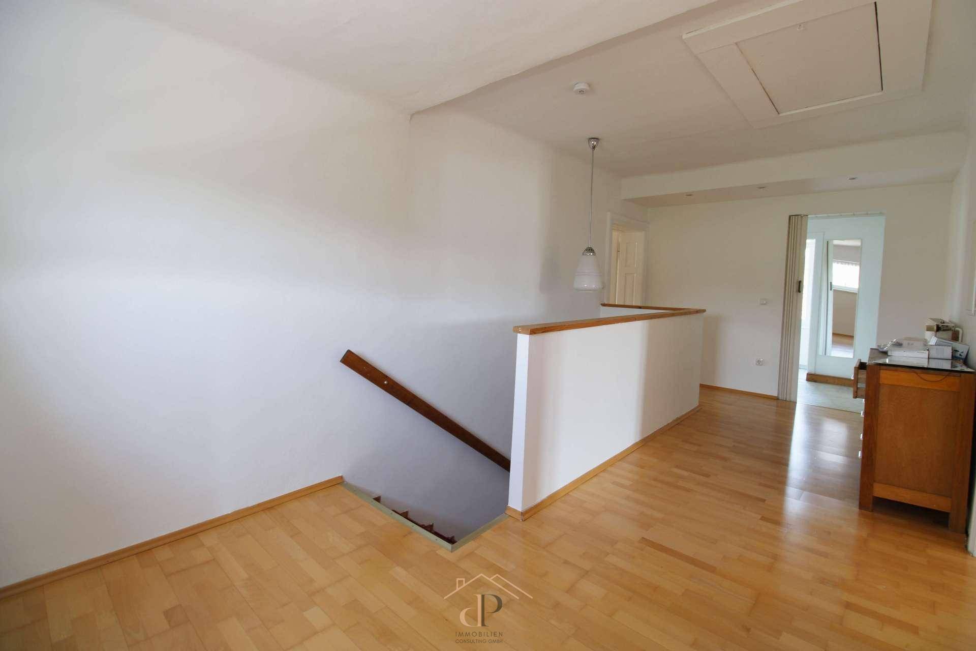 Heller Flur mit Holztreppe und Laminatboden, verbindet die verschiedenen Wohnbereiche des Hauses.
