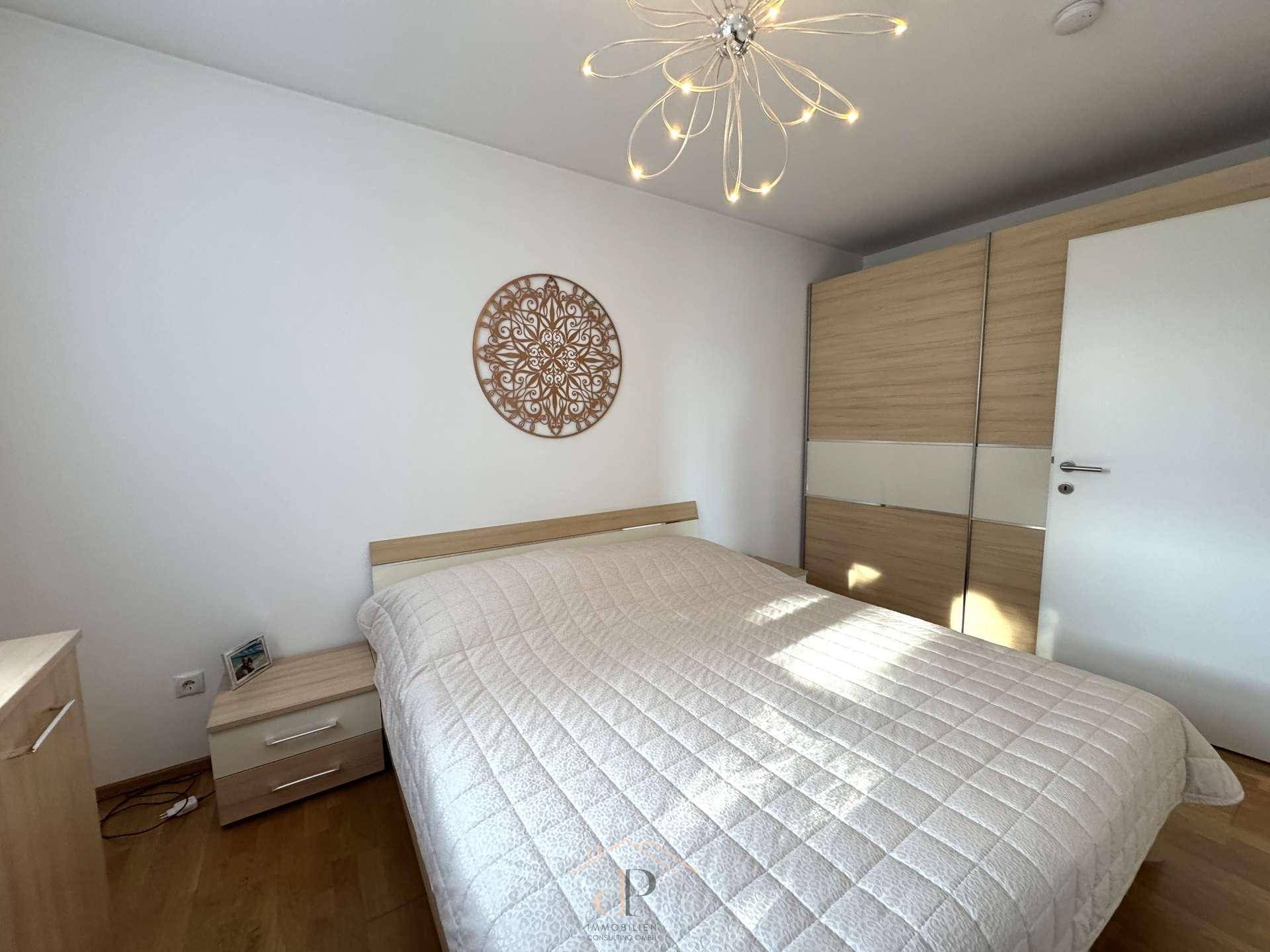 Helles Schlafzimmer mit Doppelbett, Nachttischen und integriertem Kleiderschrank.