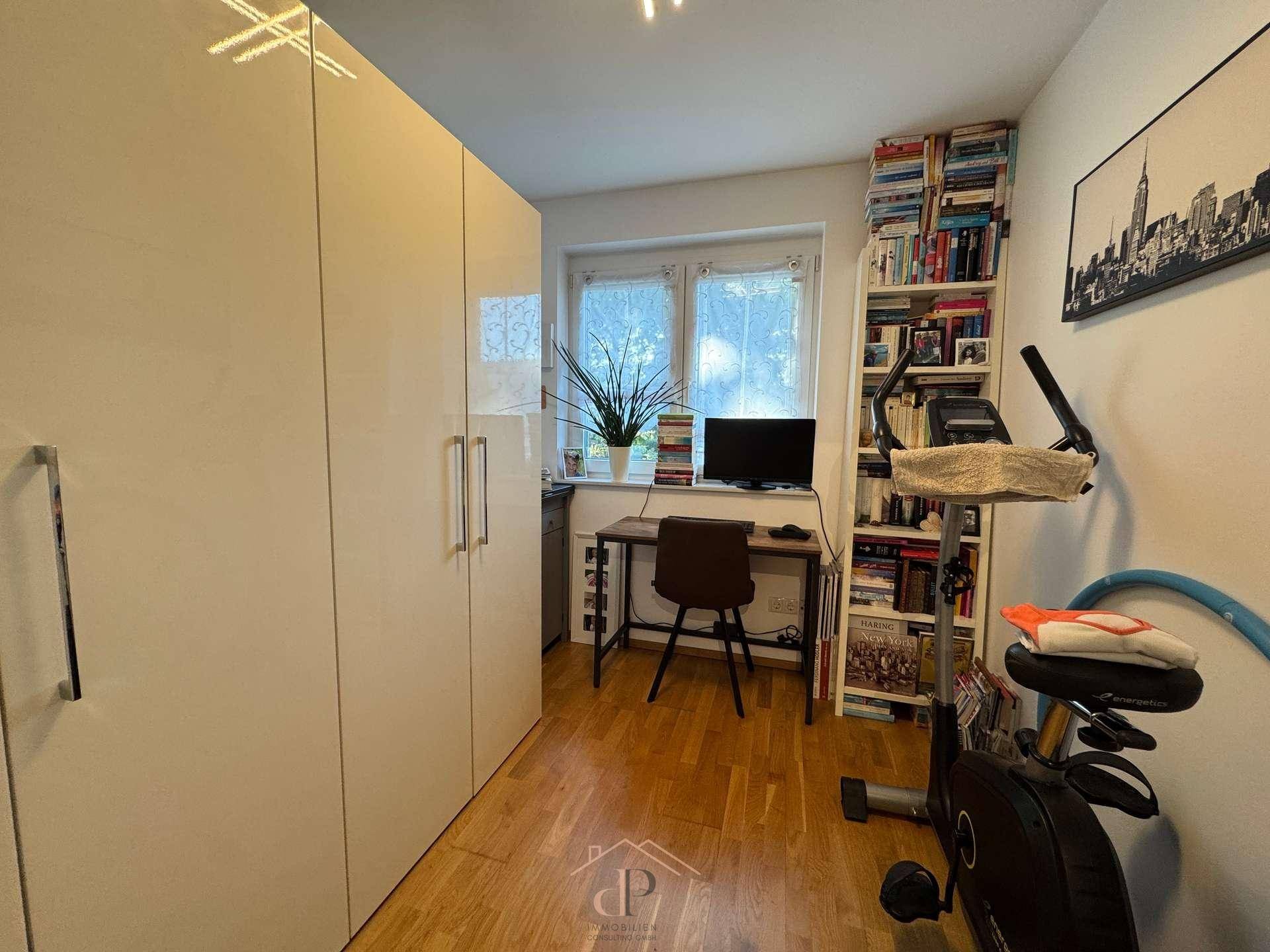 Funktional eingerichtetes Zimmer mit großem Kleiderschrank, Schreibtisch und Fitnessgerät.