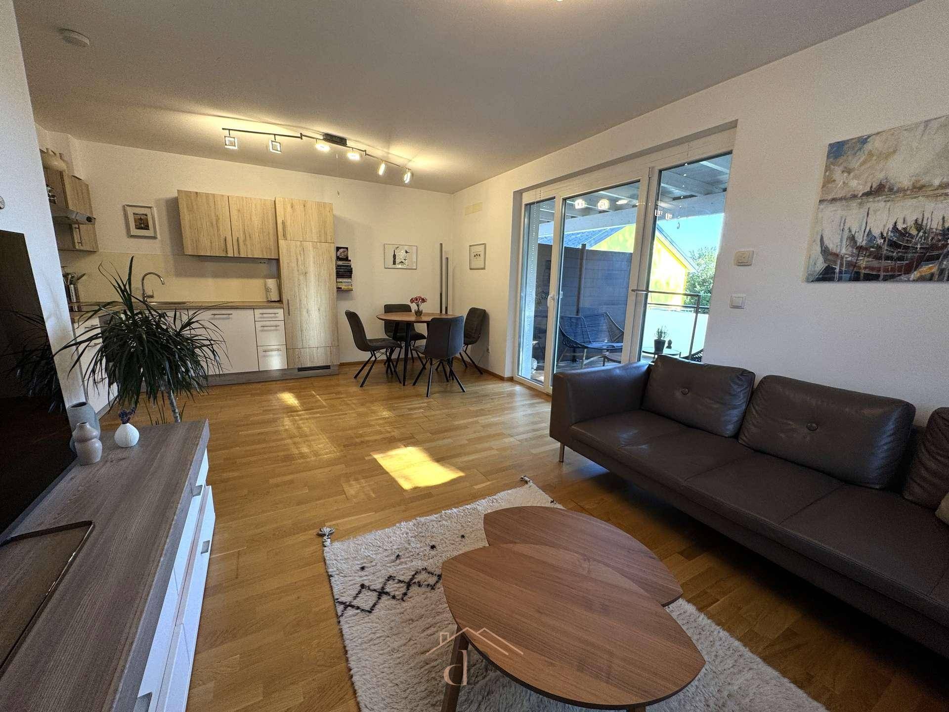Heller offener Wohn- und Essbereich mit integrierter Küche und Zugang zur Terrasse.