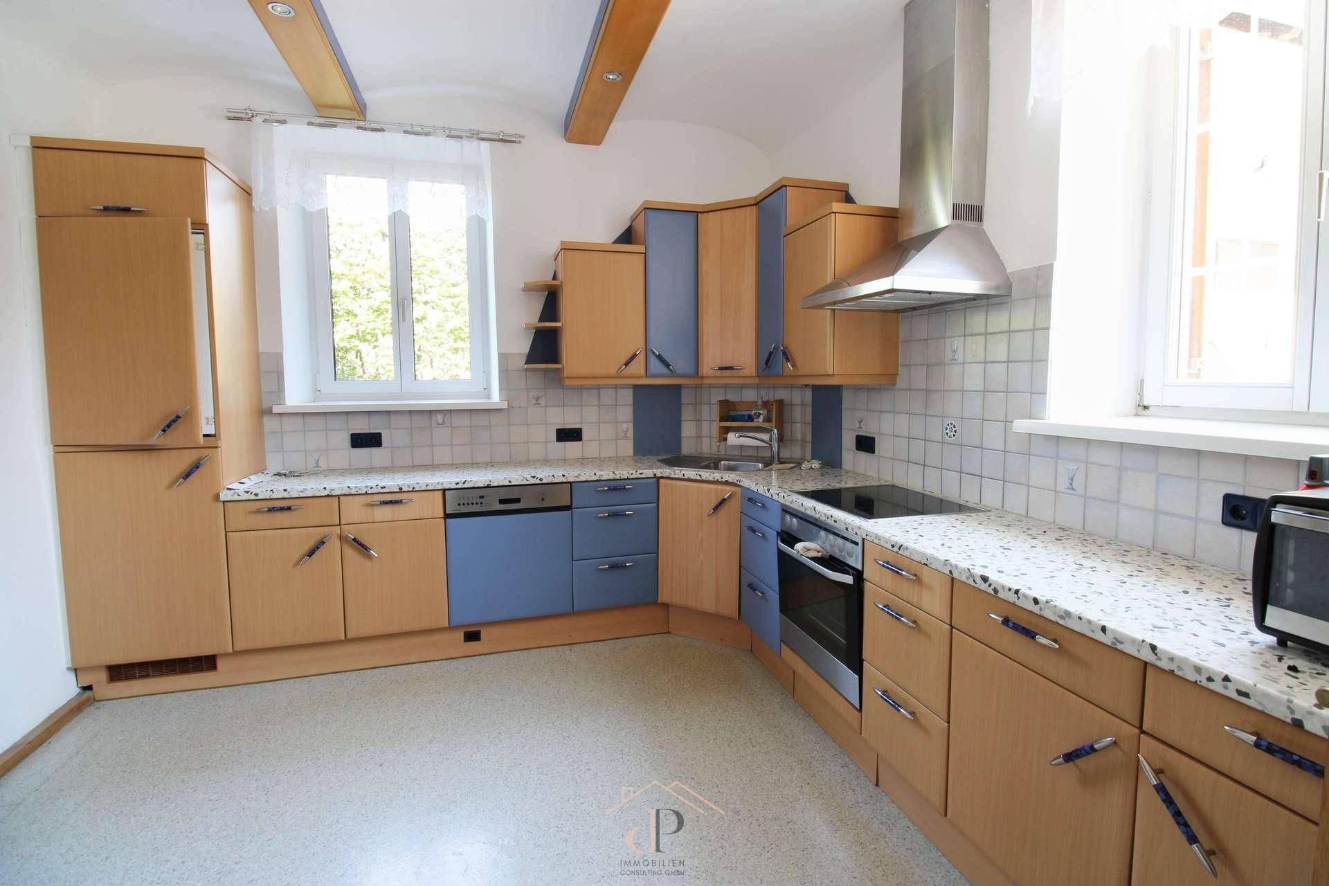 Helle Küche mit Holz- und blauen Fronten, gefliestem Spritzschutz und integrierten Küchengeräten.