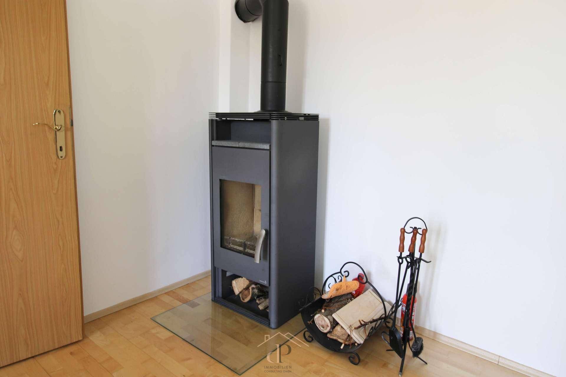 Gemütliches Wohnzimmer mit modernem Holzofen und Holzboden, ideal für kalte Abende.