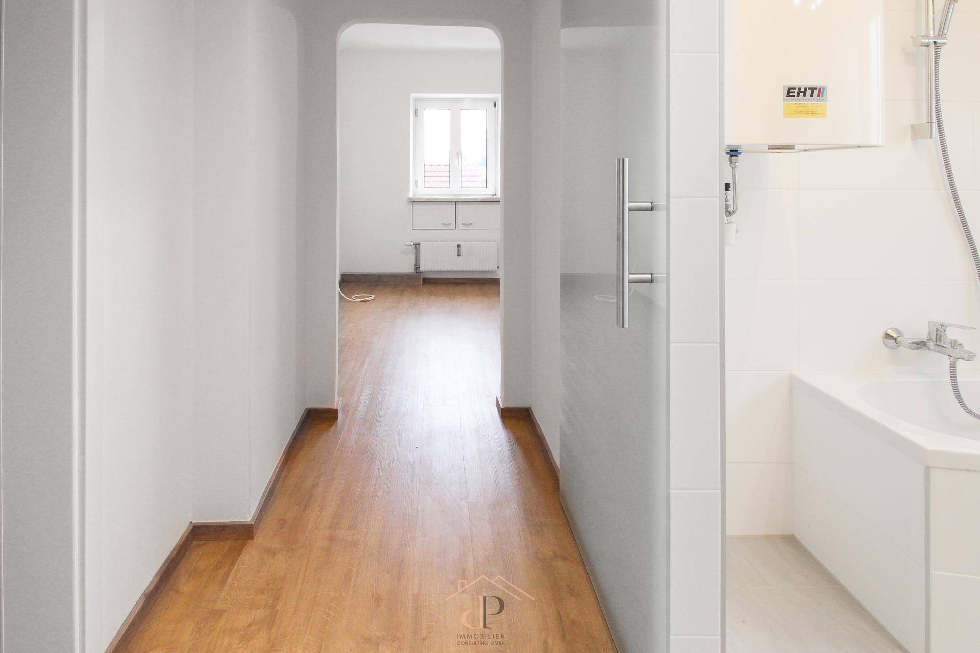 Heller Flur mit Holzoptikboden, der zu weiteren Räumen und einem Badezimmer führt.
