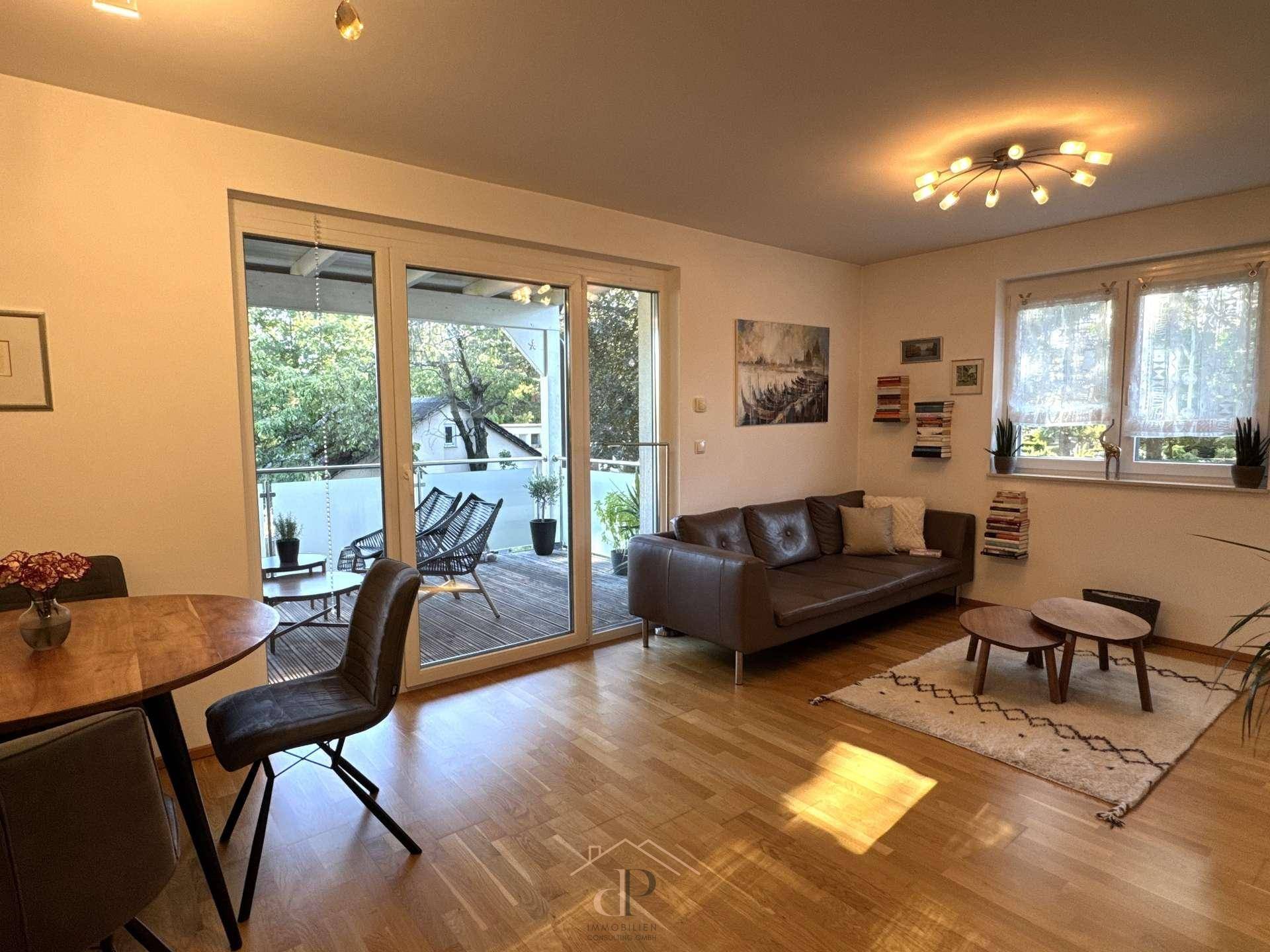 Gemütlicher Wohnbereich mit braunem Sofa, Esstisch und großen Schiebetüren zur Terrasse.