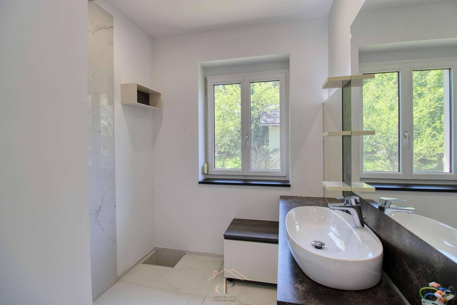Helles Badezimmer mit modernem Waschbecken, großer Dusche und Fenster, hochwertig ausgestattet.
