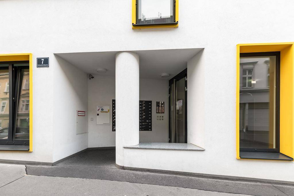 Eingangsbereich des modernen Gebäudes mit Säule und gelben Fensterrahmen.