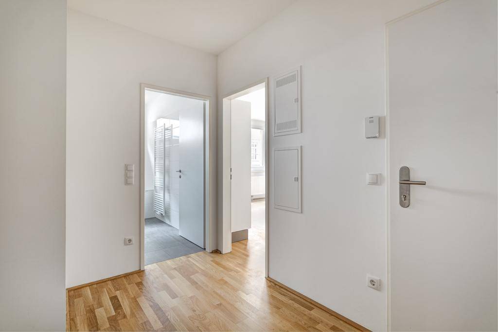 Heller Flur mit Holzboden und mehreren Türen, die zu den angrenzenden Räumen führen.