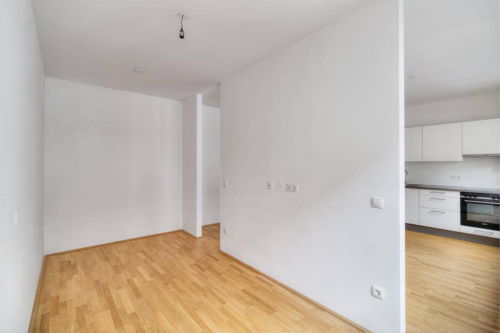 Blick vom Küchenbereich in den hellen Wohnraum mit Holzboden und offener Gestaltung.