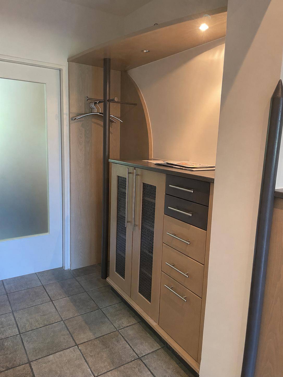 Eingebauter Garderobenschrank mit Ablageflächen und Kleiderstange im Flur.