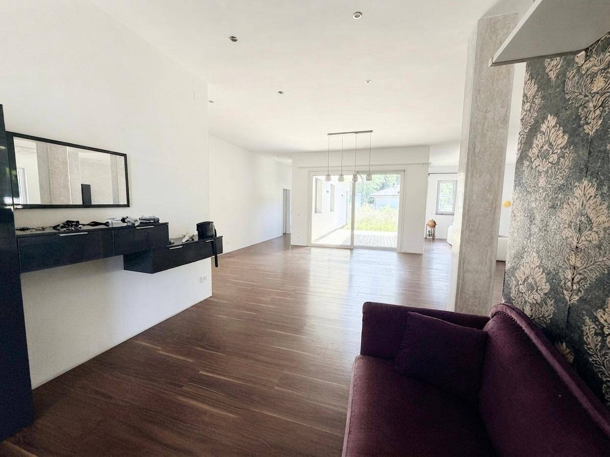 Heller Wohnbereich mit Holzboden, moderner Einrichtung und Zugang zur Terrasse durch große Schiebetüren.