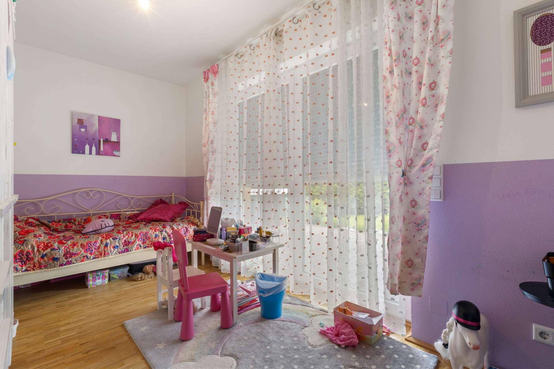 Kinderzimmer mit Bett, Schreibtisch, Parkettboden und Zugang zum Garten.
